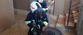 Strażacy OSP w trakcie ćwiczeń praktycznych w ramach szkolenia podstawowego strażaków OSP - dwóch strażaków w aparatach powietrznych podczas zajęć z gaszenia pożarów wewnętrznych