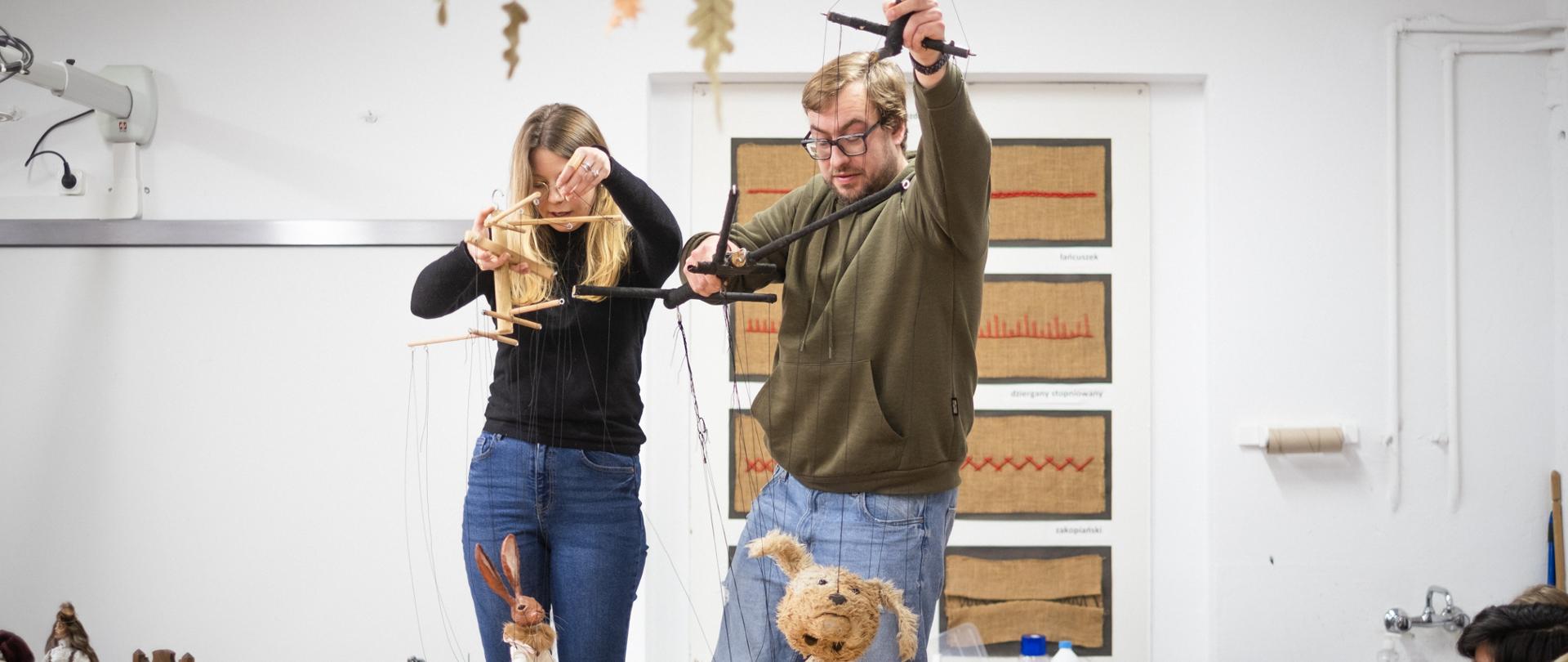 Kasia Rogowska i Łukasz Puczko animują swoje lalki na stole w pracowni zabawki miękkiej w budynku PLSP.