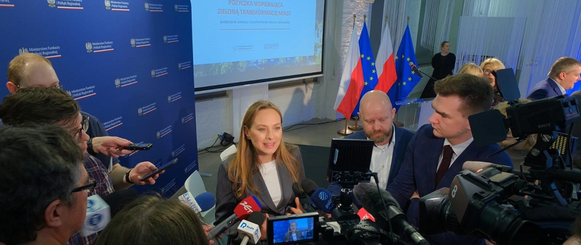 Minister funduszy i polityki regionalnej Katarzyna Pełczyńska-Nałęcz stoi w otoczeniu dziennikarzy