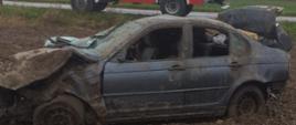 Uszkodzony samochód osobowy marki BMW stojący na polu. Auto całkowicie zniszczone, 
