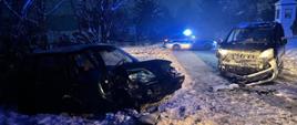 Zdjęcie przedstawia dwa rozbite samochody osobowe na zaśnieżonej drodze.