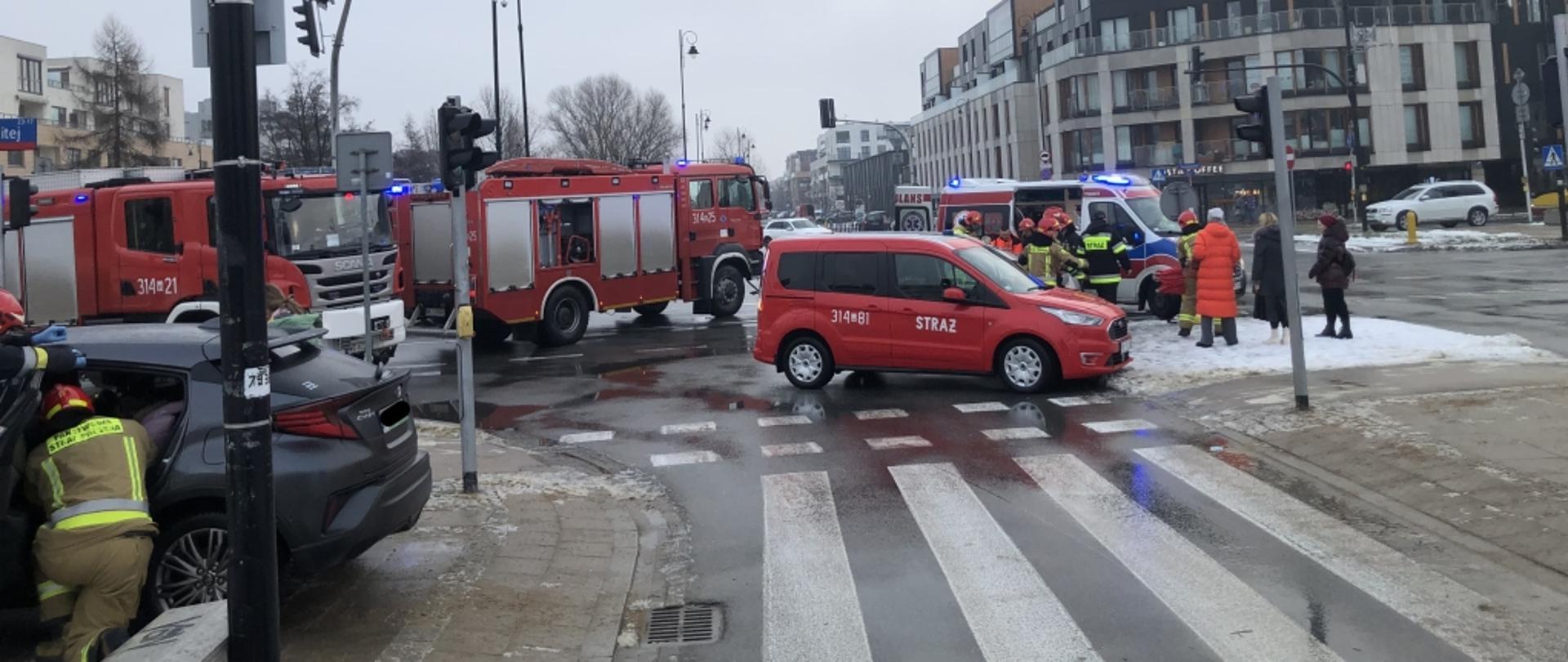 Na zdjęciu na pierwszym planie z lewej strony widoczny jest samochód marki Toyota, przy którym znajdują się dwaj ratownicy PSP. Na drugim planie znajduje się samochód osobowy PSP o numerach bocznych 314-81, za którym widać ratowników PSP i ratowników medycznych udzielających pomocy osobie poszkodowanej.