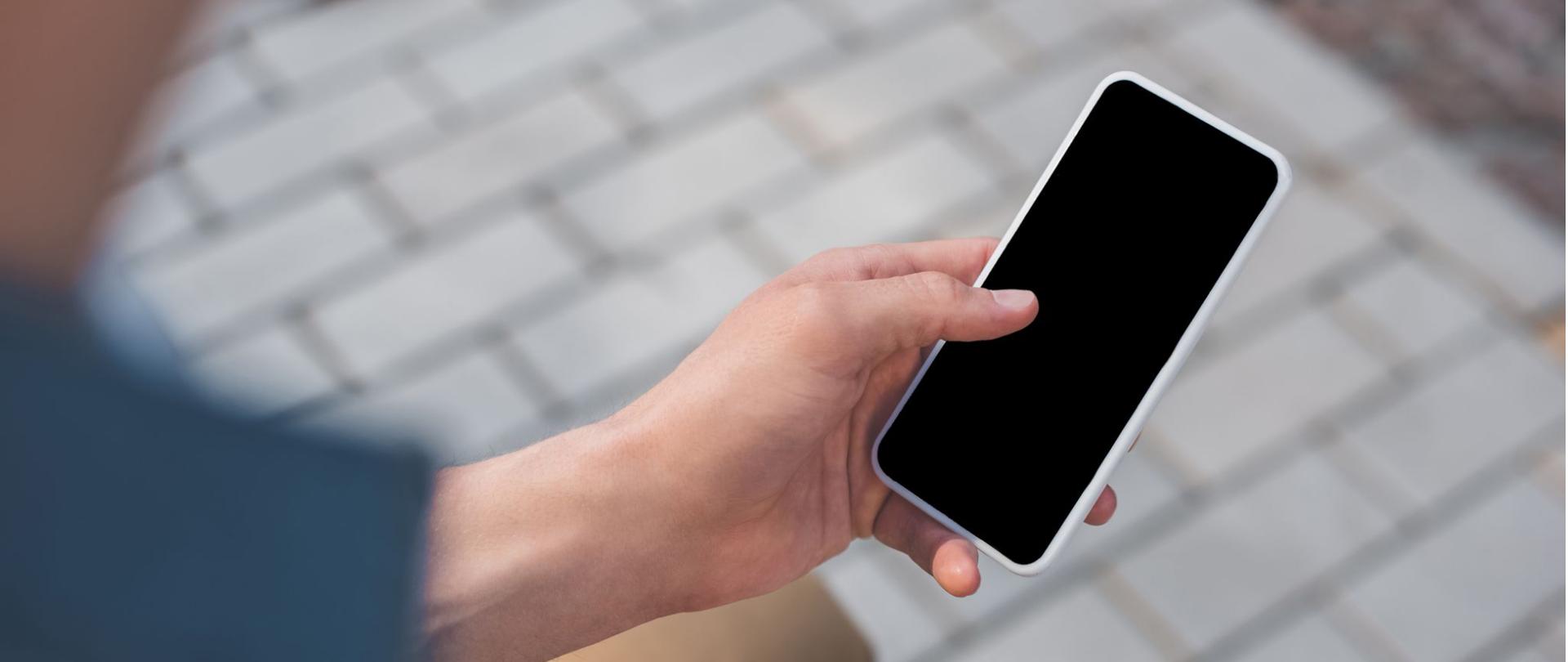 Na zdjęciu jest mężczyzna, który w ręce trzyma telefon.