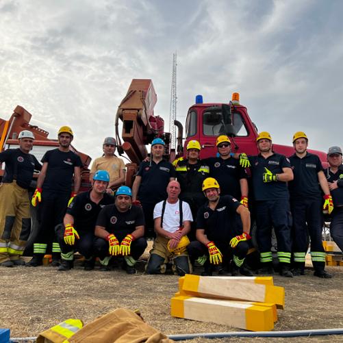 Grupa 13 mężczyzn pozuje na tle samochodu z podnośnikiem