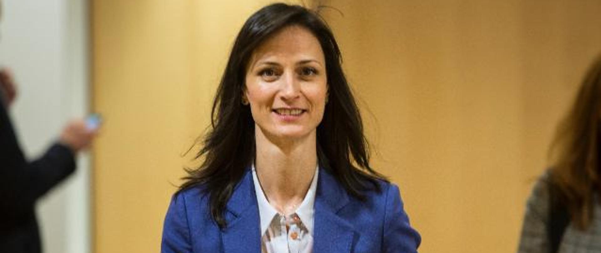 Kobieta w niebieskiej marynarce niosąca dokumenty