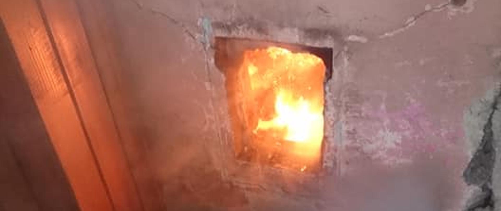 Na zdjęciu znajduje się komin i wyczystka w której pali się sadza