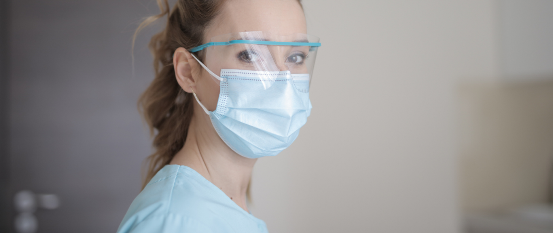 Zdjęcie twarzy młodej kobiety ubranej w maseczkę i przyłbicę