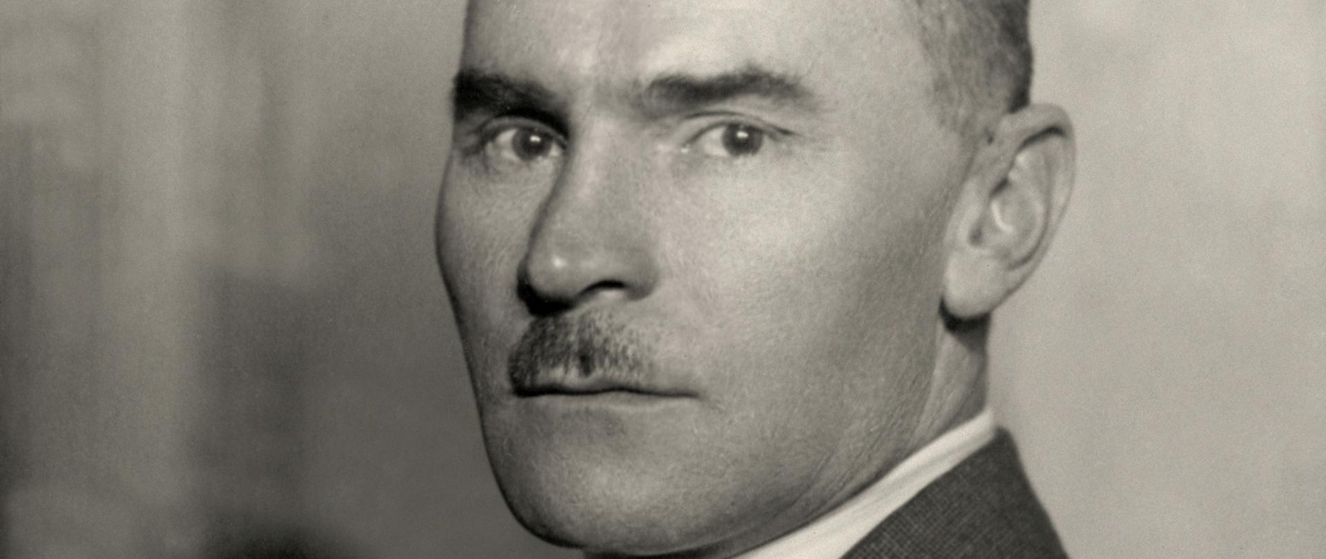 Jan Dąbski - Czarno-biały portret mężczyzny, półprofil, ciemne włosy, drobne wąsy, ciemna marynarka, biała koszula i ciemny krawat.