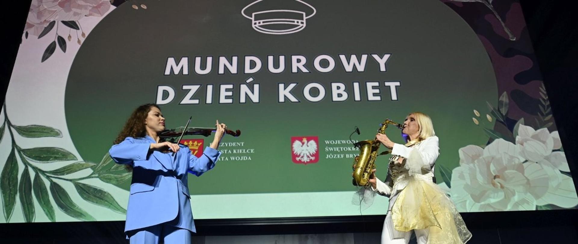 Mundurowy Dzień Kobiet - dwie kobiety muzycy grają na instrumentach na scenie na tle wyświetlonego napisu Mundurowy Dzień Kobiet