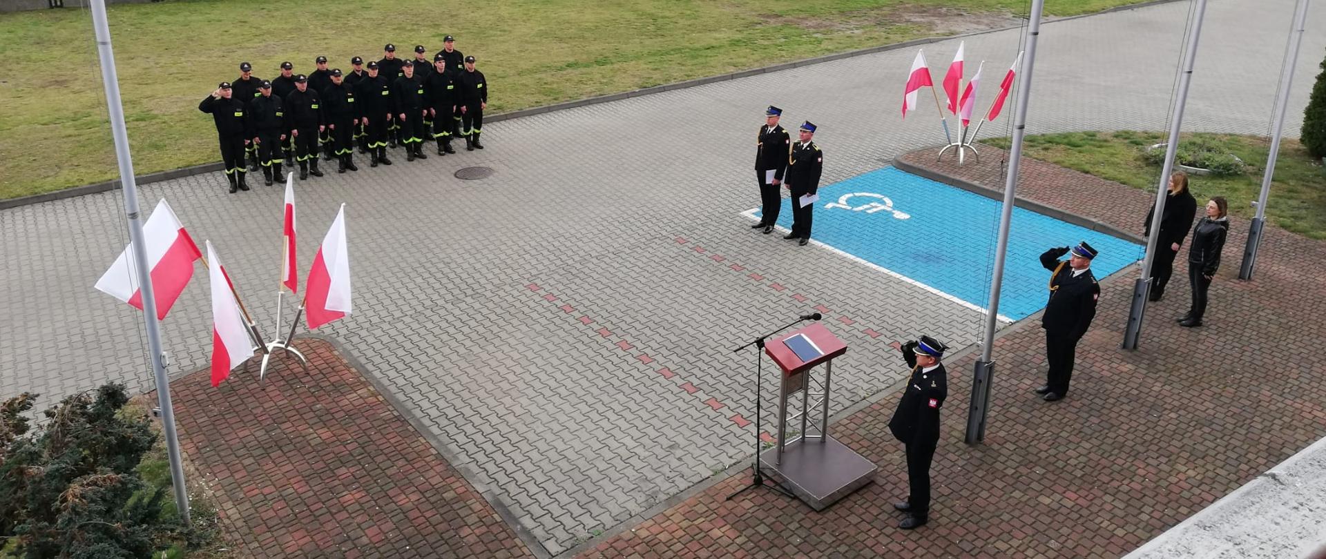 Funkcjonariusze salutujący do flagi podczas śpiewania hymnu narodowego.