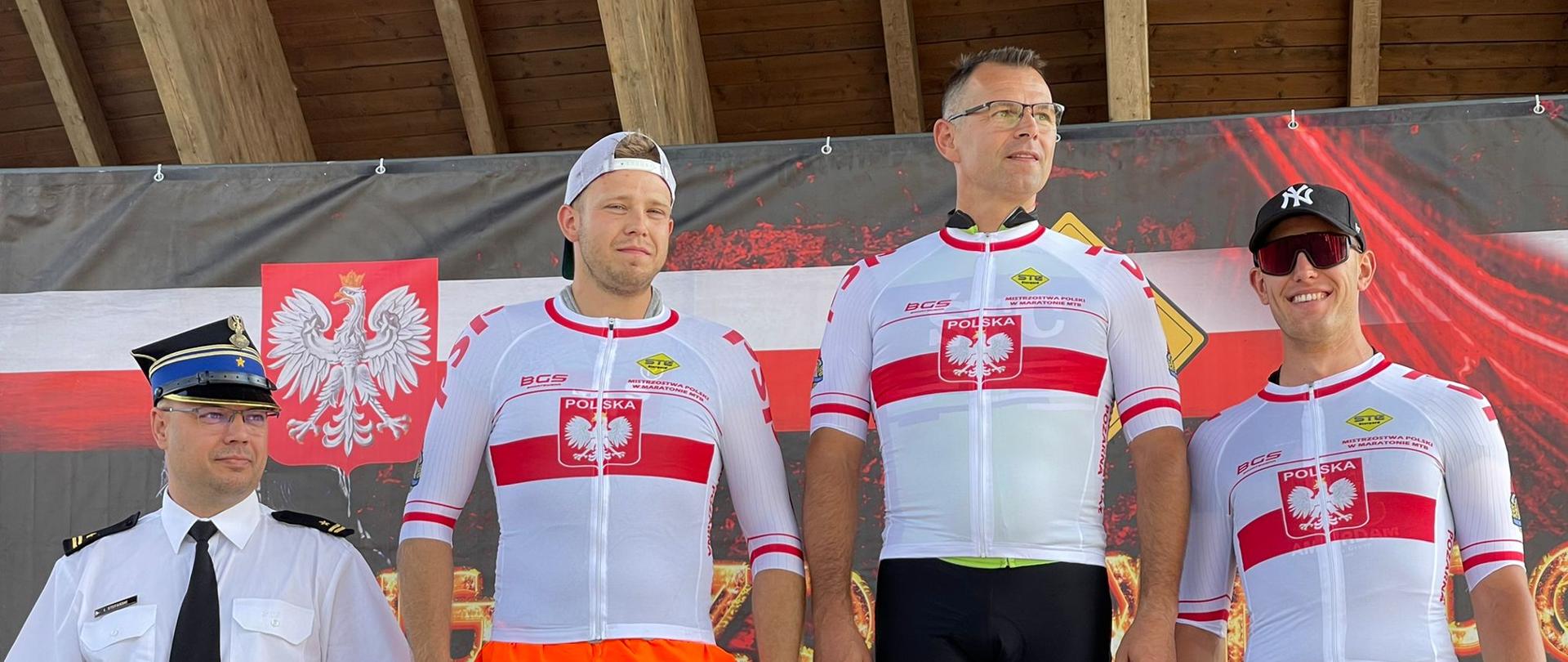 Osoby w strojach cywilnych i jeden strażak w mundurze stoją w szeregu.