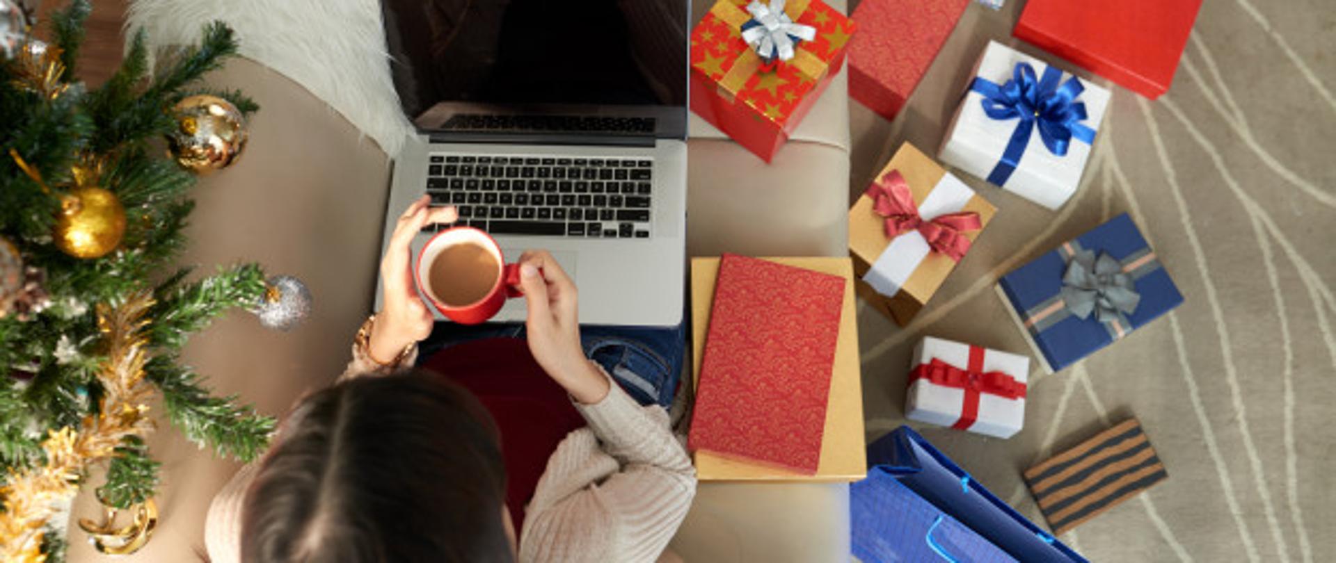 kobieta z laptopem przy choince i prezentach
