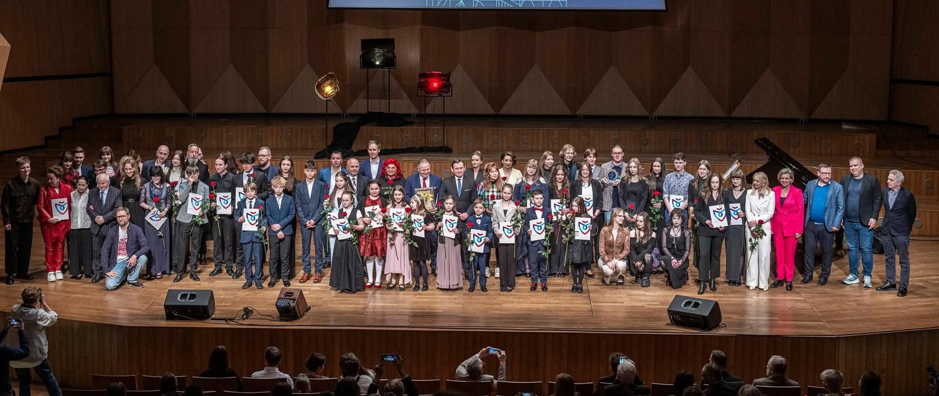 Uczniowie ZPSM nagrodzeni, stoją na scenie filharmoni koszalińskiej