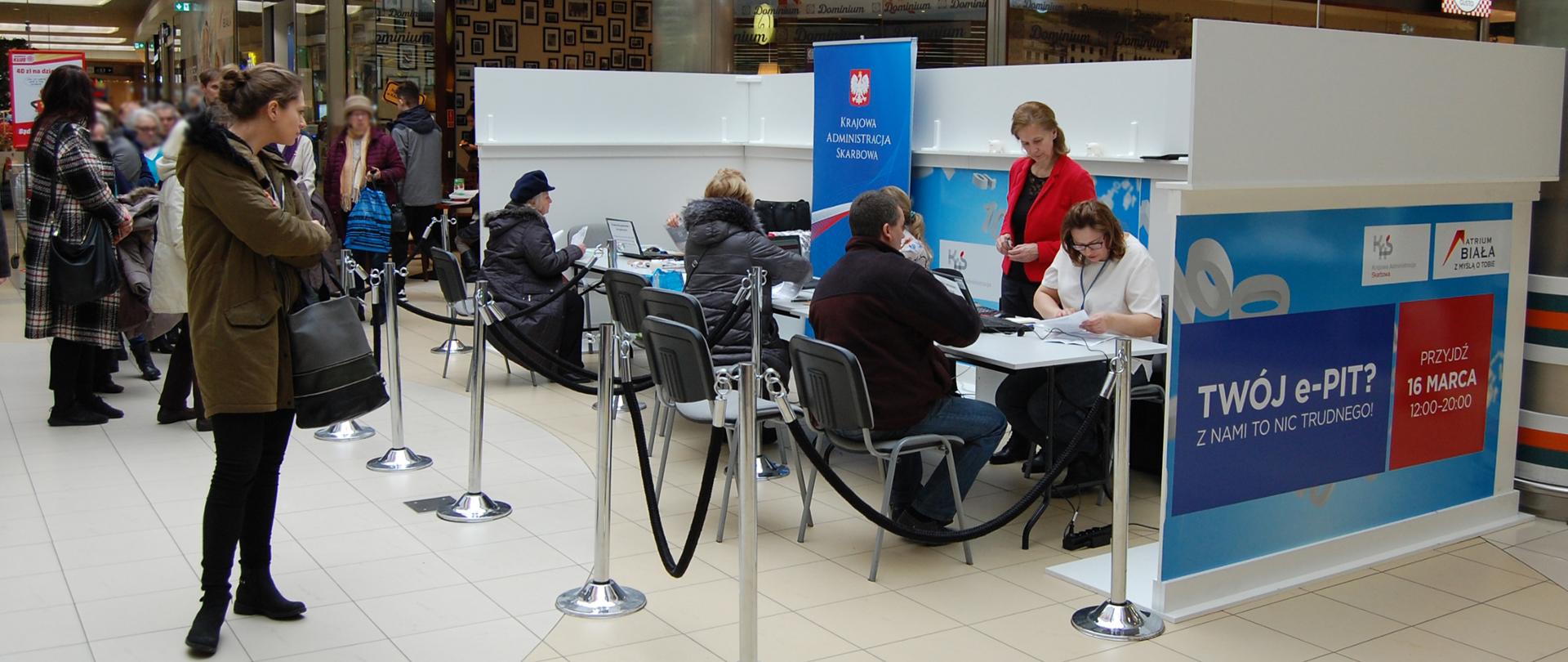 Pracownicy urzędu skarbowego udzielają informacji podatnikom przy stoisku w galerii handlowej