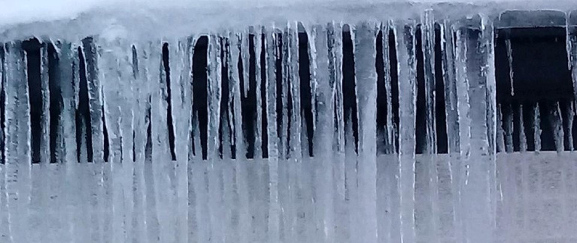 Na zdjęciu widoczne sople lodu na dachu budynku.