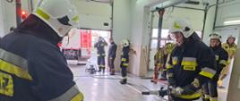 Zdjęcia przedstawia strażaków OSP ubranych w ubrania specjalne koloru granatowego oraz hełmy strażackie, wykonujących zadanie ze sprzętem hydraulicznym.