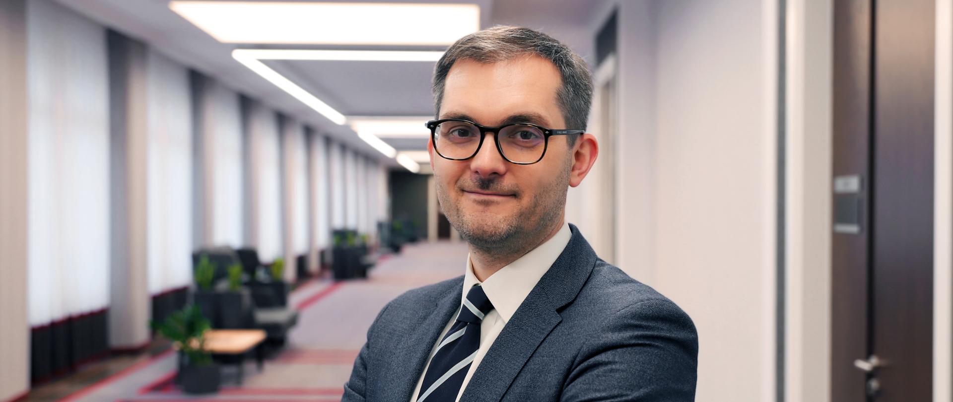 Zdjęcie przedstawiające wiceministra Marka Niedużaka na szarym tle. 