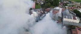 Zdjęcie zrobione z drona. Przedstawia widok z góry tartaku. Nad zakładem unosi się gęsty dym