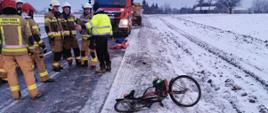 Na zdjęciu widać miejsce potracenia, rower oraz strażaków. Na drugim planie wóz straży pożarnej 
