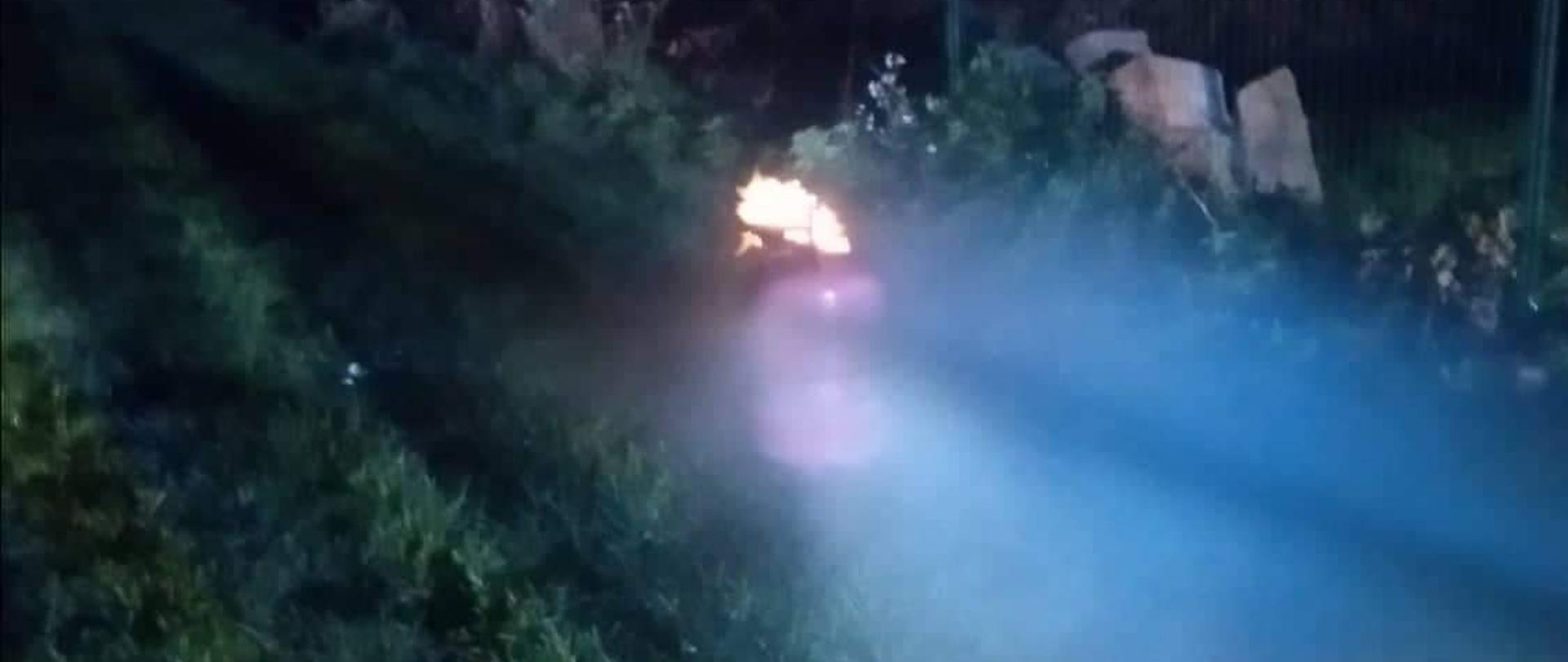 Na trawie stoi butla z gazem z której wydobywa się ogień