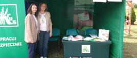 Stoisko KRUS. W centrum zielony namiot opatrzony hasłem: „Pracuj Bezpiecznie”. Po lewej baner z logiem Kasy. Pod namiotem stoliki wyłożone broszurami i materiałami prewencyjnymi. Po lewej pracownicy KRUS.