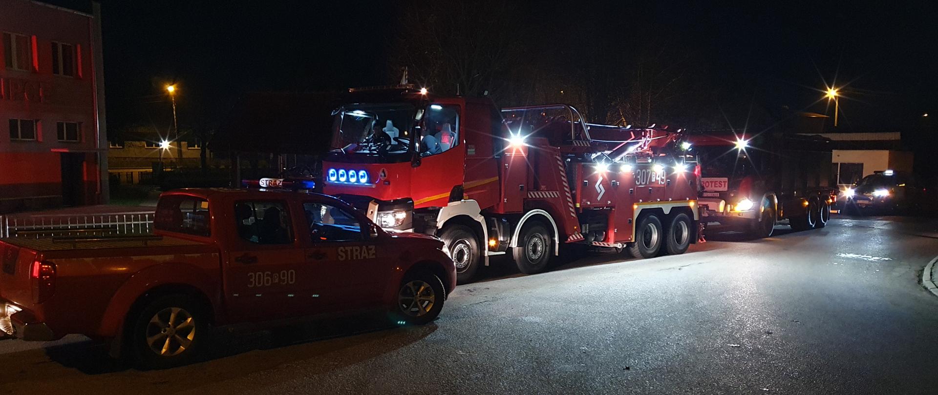 Na zdjęciu widoczne są czerwone samochody straży pożarnej w punkcie przyjęcia sił i środków