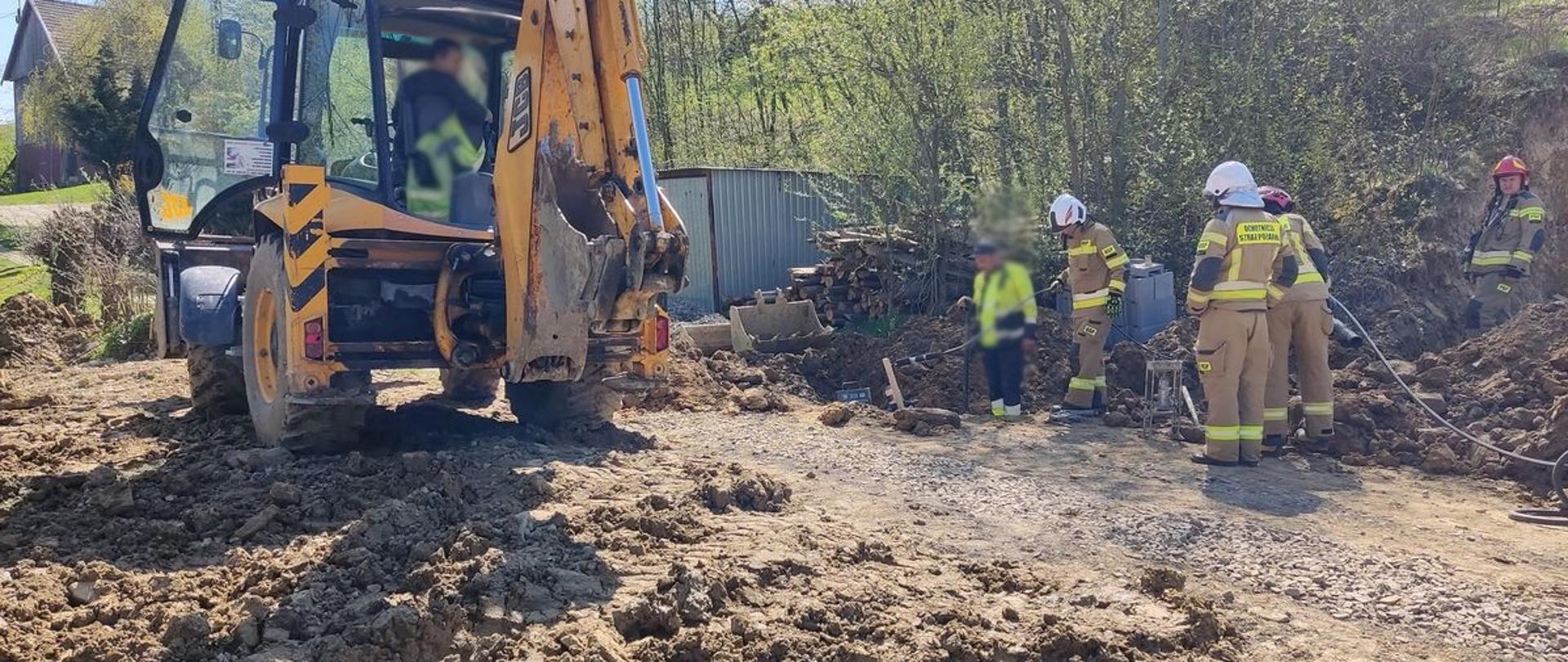 Koparka oraz strażacy oraz wykopu
