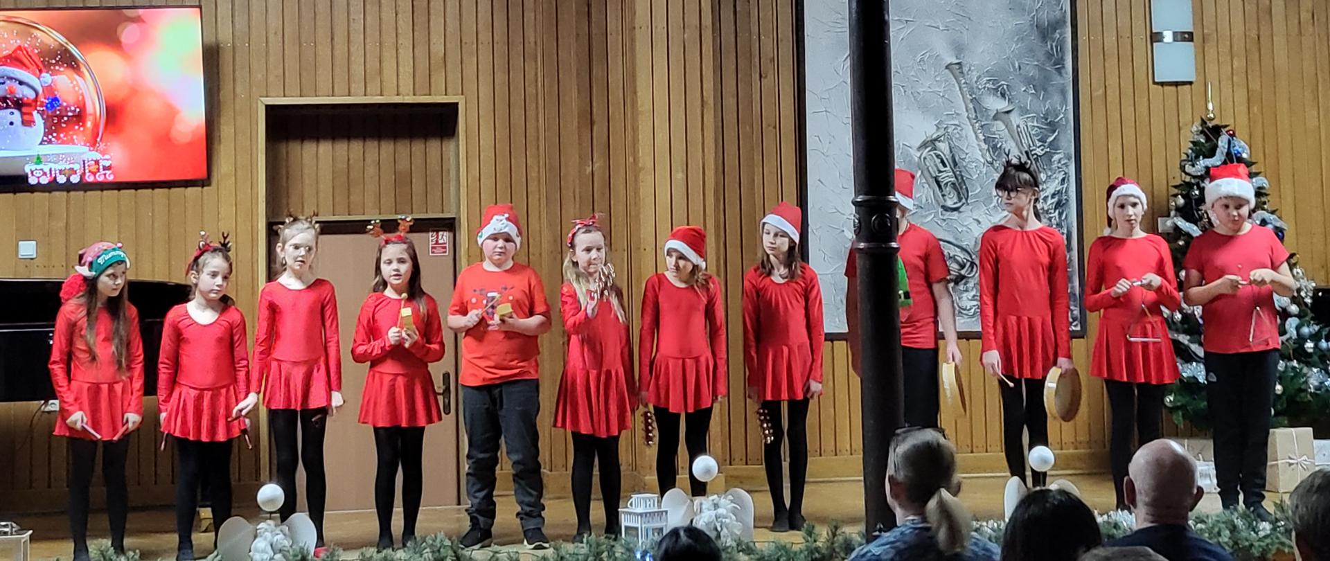 Grafika przedstawia grupę uczniów śpiewających na scenie