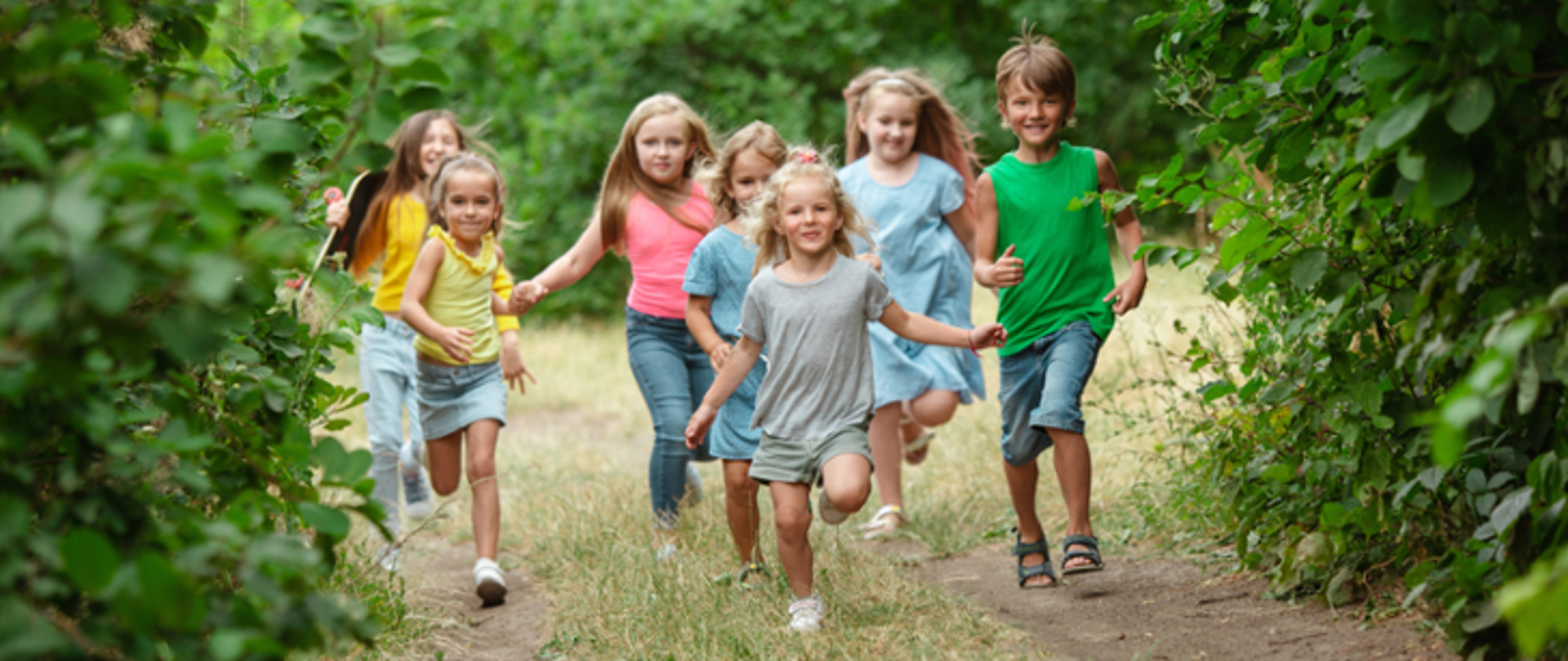 Zdjęcie przedstawia biegnące, uśmiechnięte dzieci.