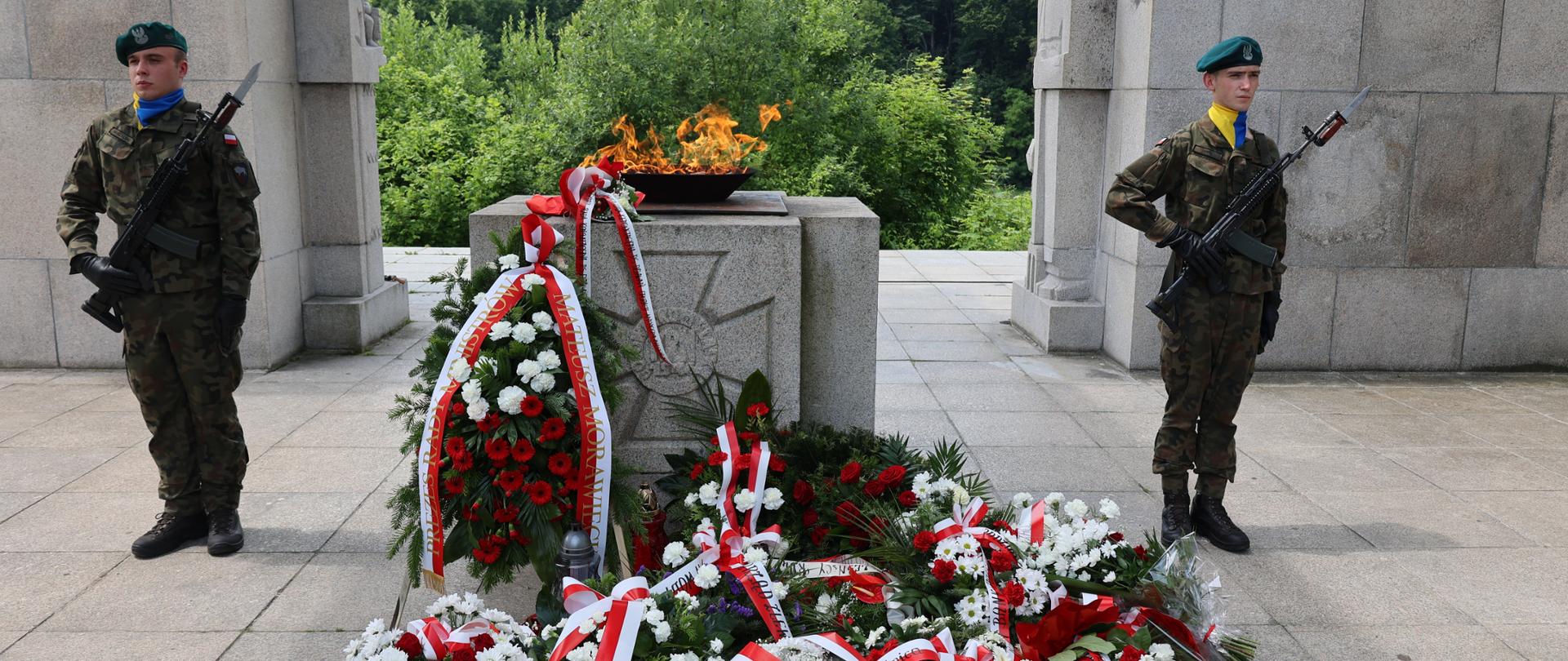 Pomnik Powstańców Ślaskich z asystą wojskową i wiązankami kwiatów.