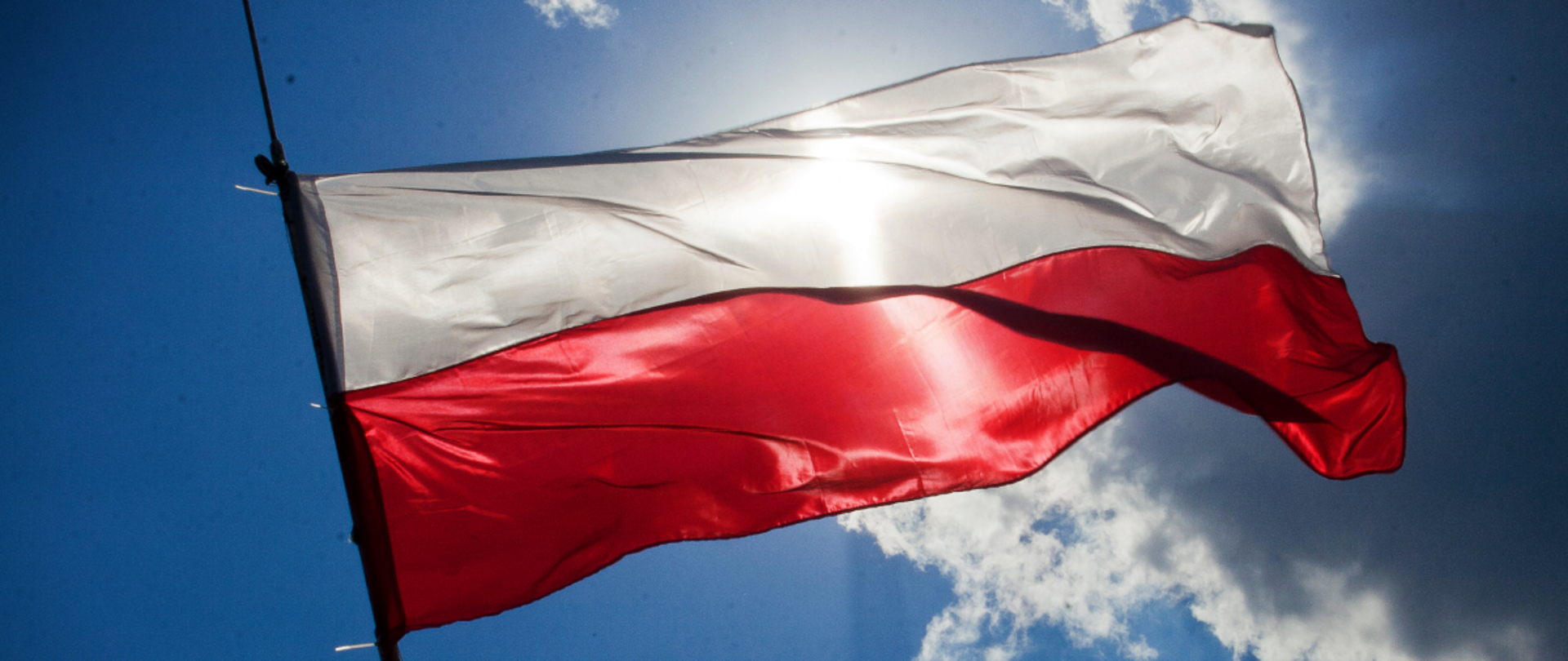Biało-czerwona flaga na tle nieba z chmurami