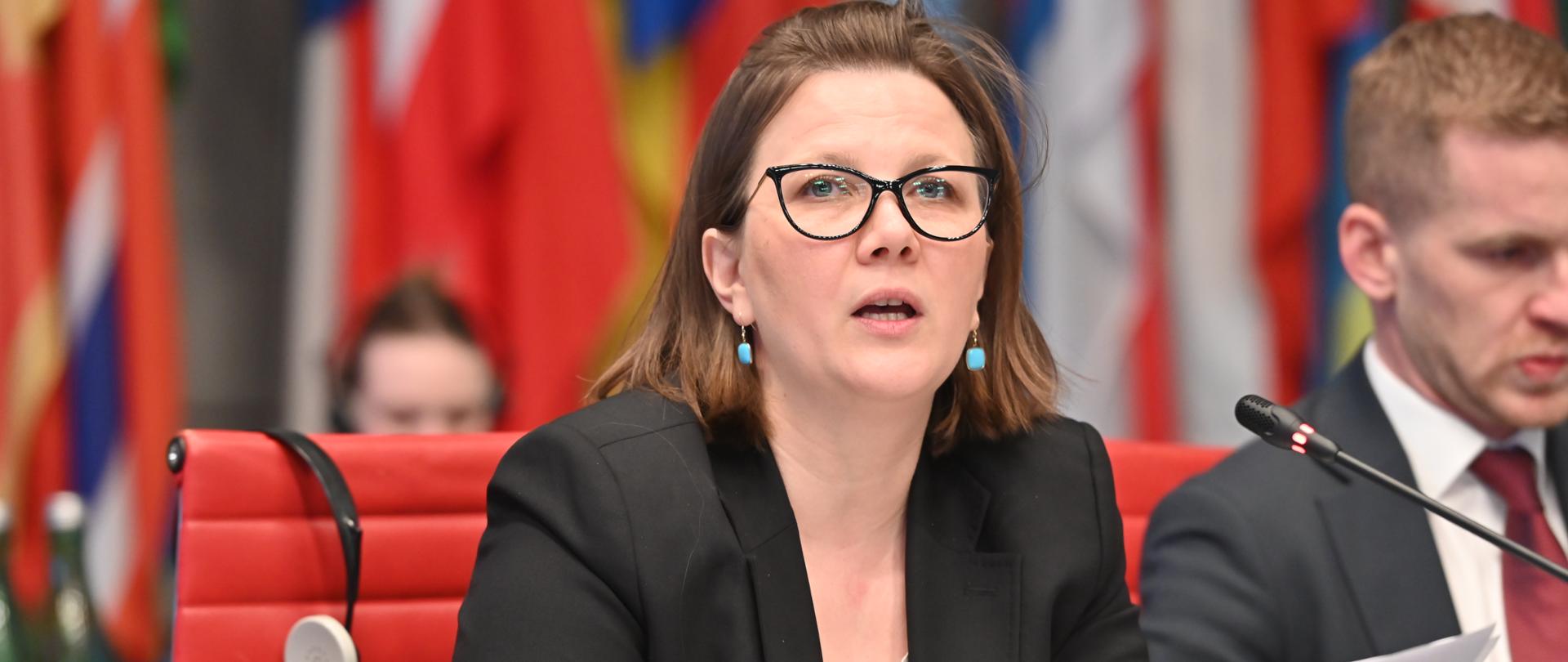 Kobieta przemawiająca do mikrofonu w trakcie posiedzenia 