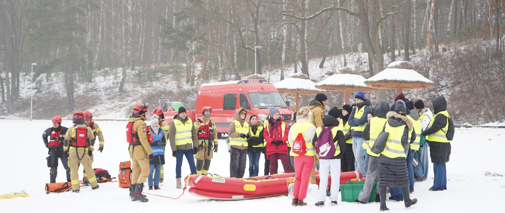 Na zdjęciu widać strażaków w trakcie prowadzenia akcji prewencyjnej z młodzieżą nad jeziorem. 