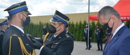 Zdjęcie przedstawia moment wręczenia odznaczenia jednemu z radomskich strażaków przez Zastępcę Mazowieckiego Komendanta Wojewódzkiego Państwowej Straży Pożarnej w Warszawie starszego brygadiera Artura Gonerę.
