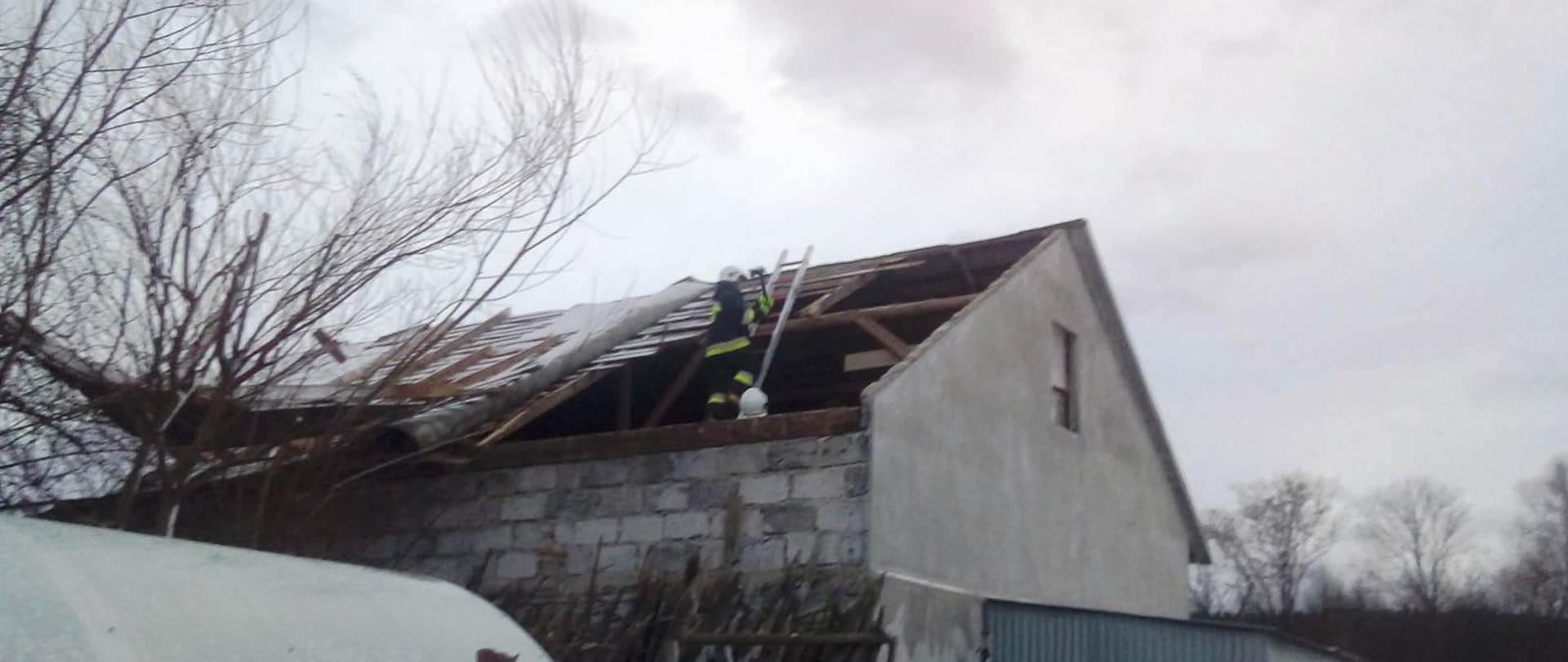 Strażacy zabezpieczają zerwany dach.