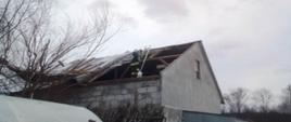 Strażacy zabezpieczają zerwany dach