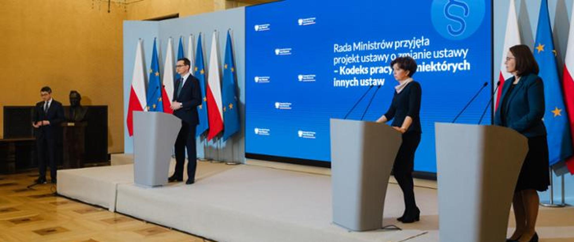 Trzy osoby stojące przy mównicach i wypowiadające się