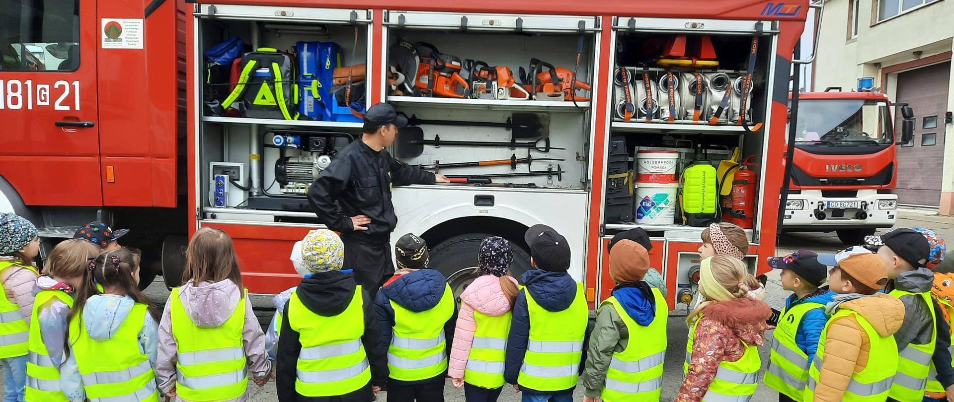 Strażak opowiada dzieciom o sprzęcie ratowniczo-gaśniczym