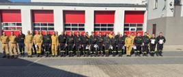 Strażacy na zdjęciu grupowy na tle budynku komendy