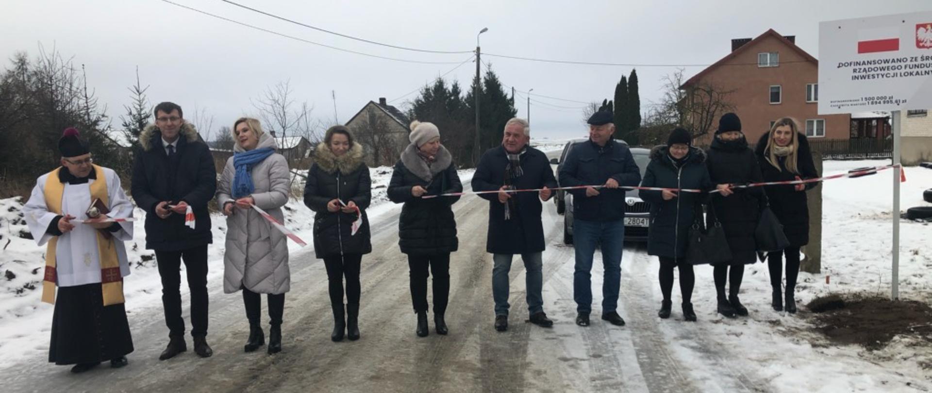 Na zdjęciu znajduje się dziesięć osób, które przecinają wstęgę na drodze