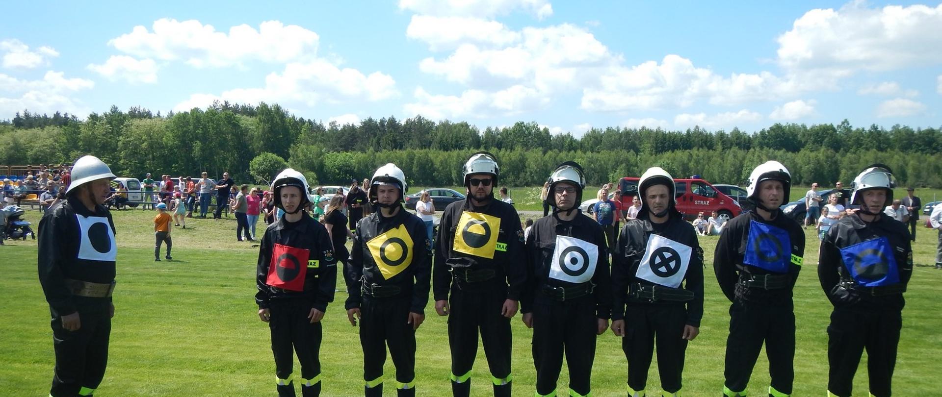 drużyna OSP na zbiórce przed startem w ćwiczeniu bojowym w tle publiczność