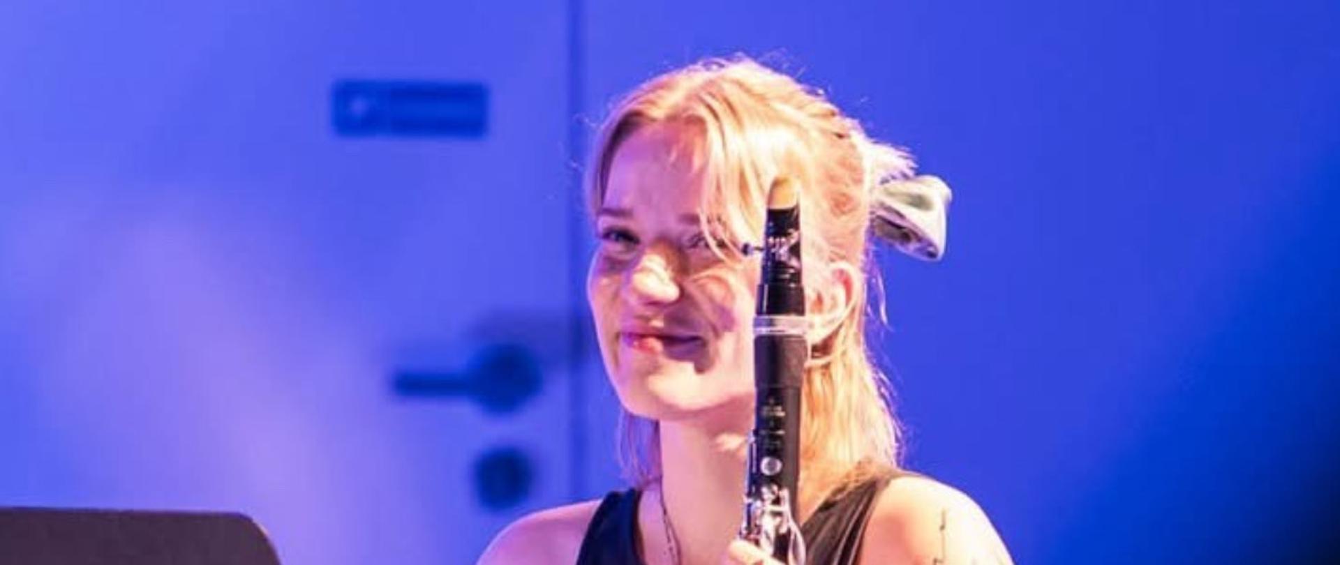 Kobieta siedzi na krześle i trzyma klarnet.