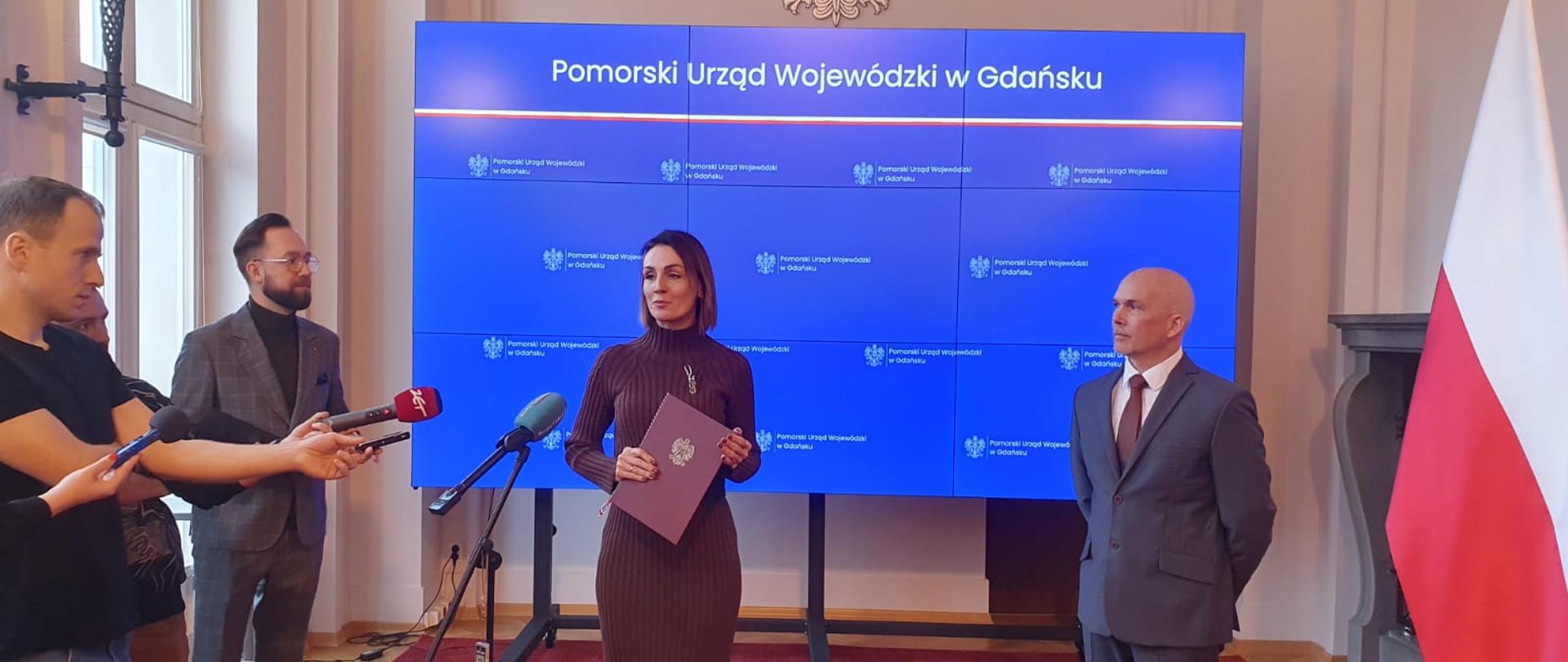 kobieta (wojewoda) wręcza powołanie konserwatorowi zabytków, sala , dziennikarze, mikrofony