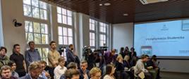 Kilkadziesiąt osób siedzi na sali konferencyjnej.