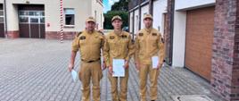 Na zdjęciu Komendant Powiatowy PSP w Pucku bryg. Wojciech Wanat, Dowódca JRG w Pucku st. kpt. Maciej Humanowski oraz mł. kpt. Grzegorz Brzeziński. Wszyscy ubrani w stroje koszarowe w kolorze piaskowym, na drugim planie budynek Komendy Powiatowej PSP w Pucku.