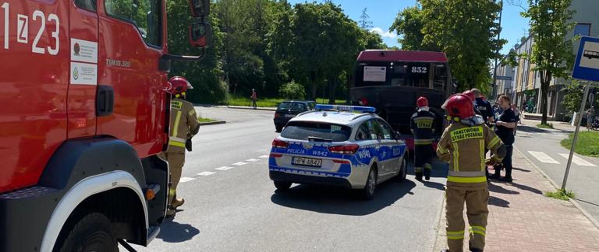 samochód pożarniczy, radiowóz policyjny oraz grupa strażaków przy autobusie