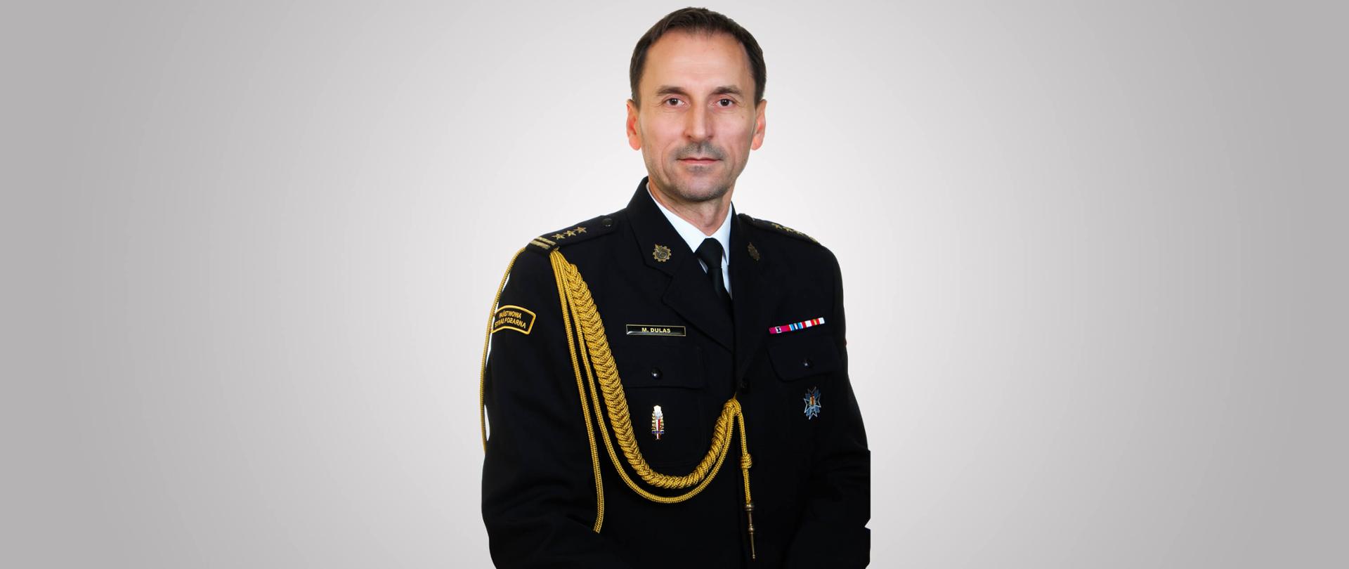 zdjęcie przedstawia starszego brygadiera Marcina Dulasa Łódzkiego Komendanta Wojewódzkiego PSP w mundurze wyjściowym. Zdjęcie portretowe