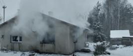Dom z którego wydobywa się dym.