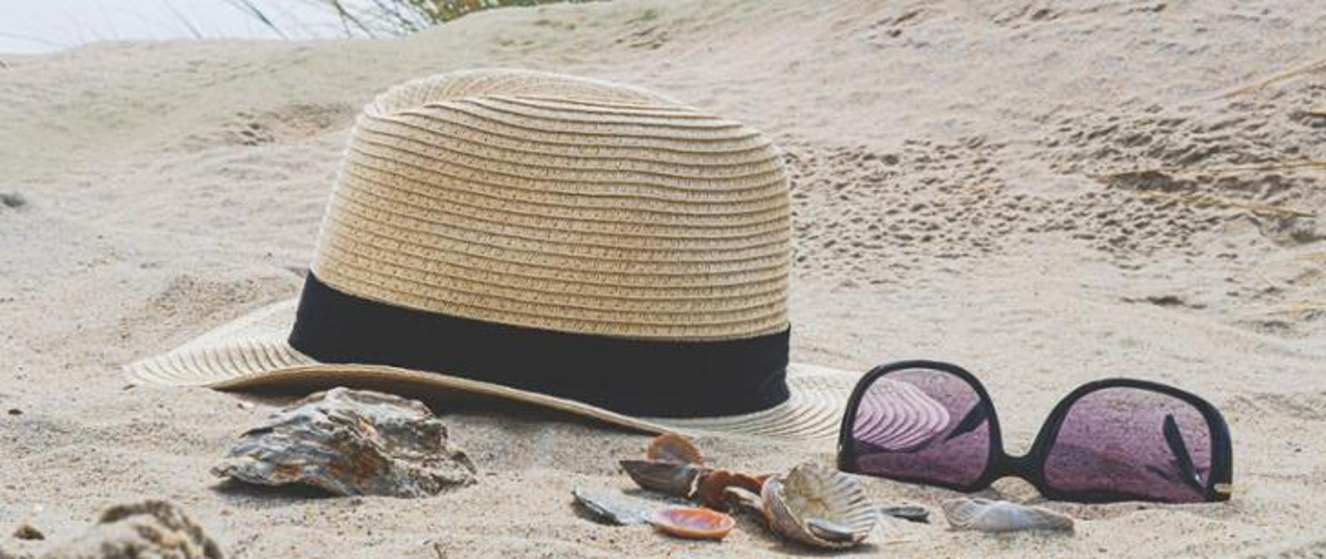 Zdjęcie kapelusza i okularów na piasku