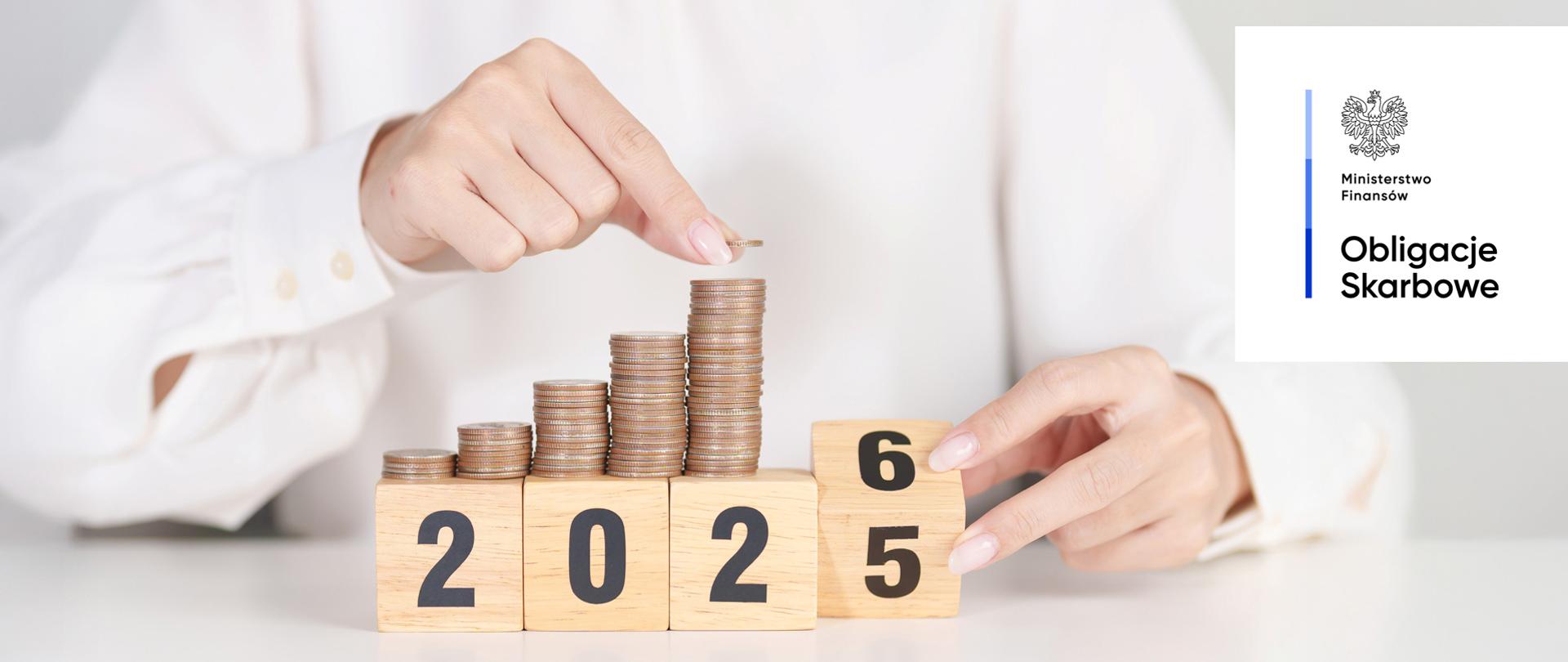 Dłonie układają monety na drewnianych kostkach kalendarza. Ministerstwo Finansów, Obligacje Skarbowe.